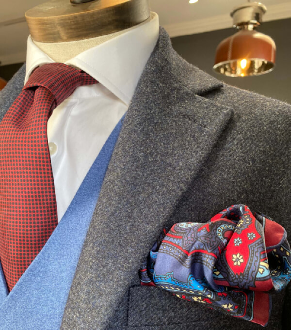 A mannequin wearing a blue suit paired with a red tie, representing a stylish formal outfit.