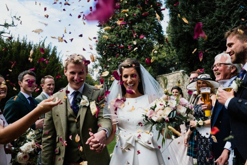 A joyful wedding celebration at a manor house, adorned with colorful confetti falling amidst happy guests and elegant decor.