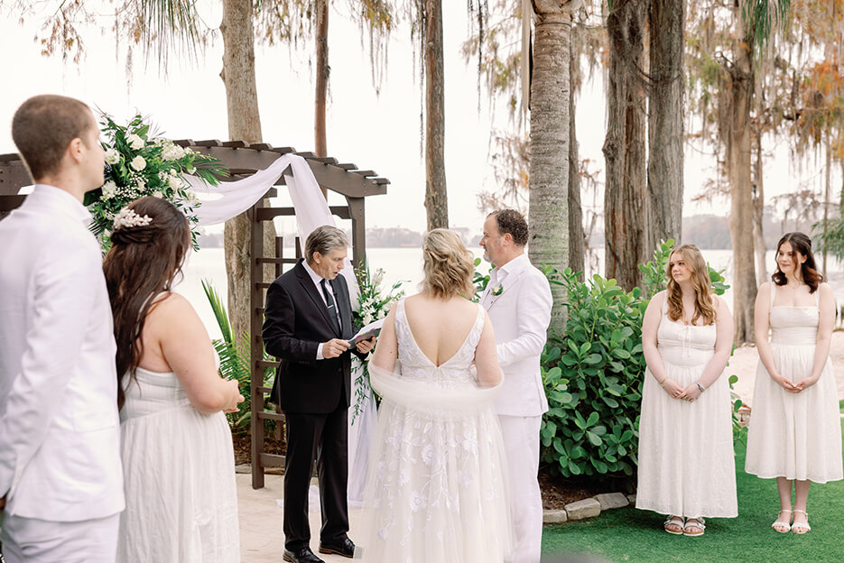 The bride and groom exchange vows in a picturesque woodland setting, creating a romantic atmosphere.